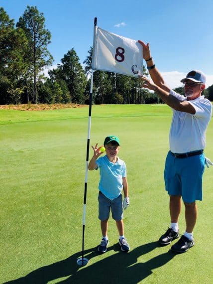 Luke Rhodes and his grandfather Ray commemorate Lukeโs ace on the 8th hole of The Cradle.